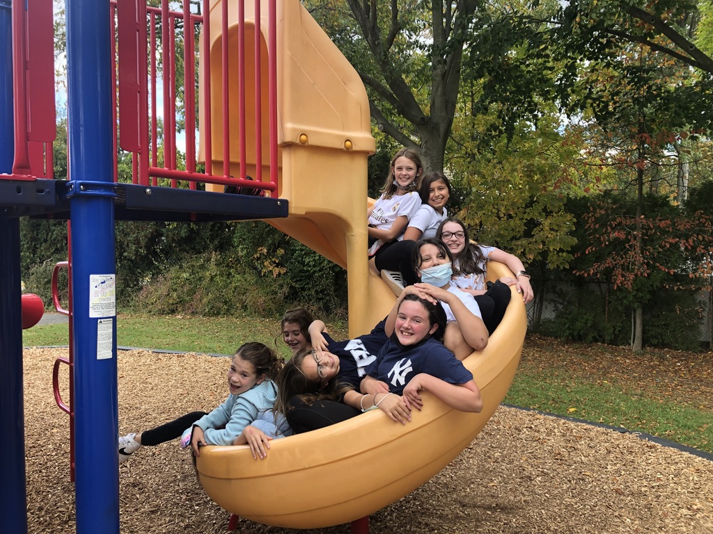 students posing on playground slide