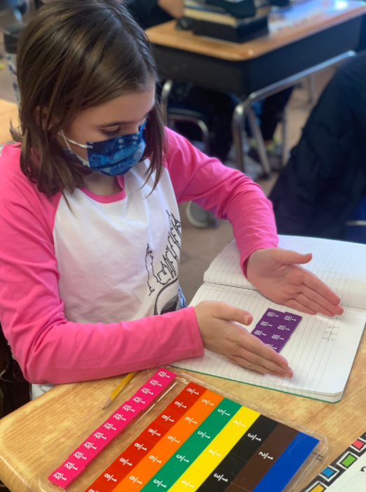 student working with fractions tiles