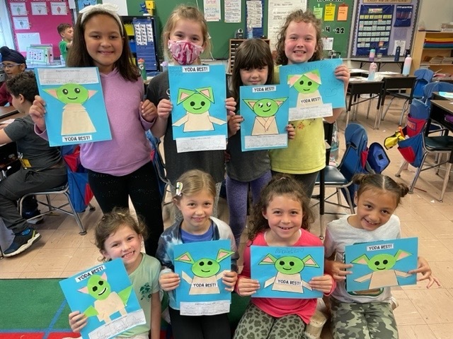 Second graders highlighting their creativity using geometric shapes to create their own Yoda character.