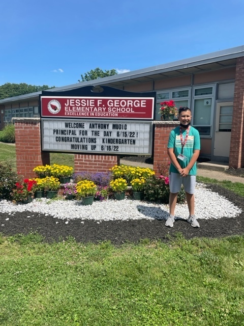 Principal for the day, Anthony Muoio standing in front of the JFG message board that welcomes hims